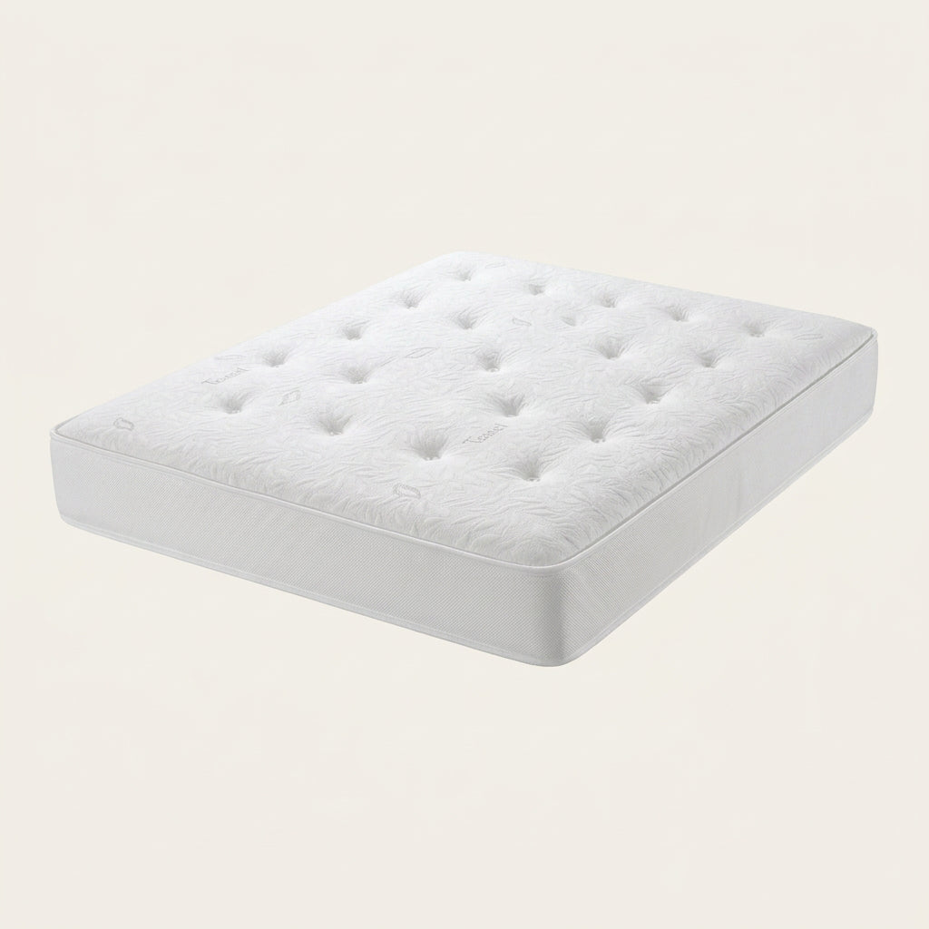 A close-up of a white tufted mattress or bedding surface with visible fabric texture, tufted buttons, and a central label reading 'afford bed centre' with 'Baby Organic Cotton' and 'Tencel' text.